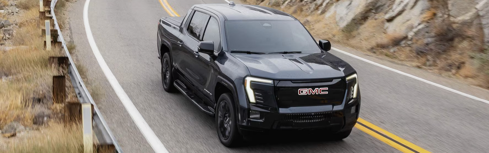 2026 GMC Sierra EV Denali showcasing premium electric performance on a scenic highway.