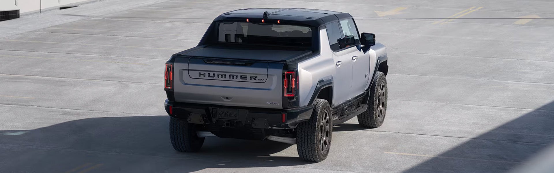 A 2026 GMC Hummer EV Pickup driving on a road, showcasing its rugged design and electric capabilities.